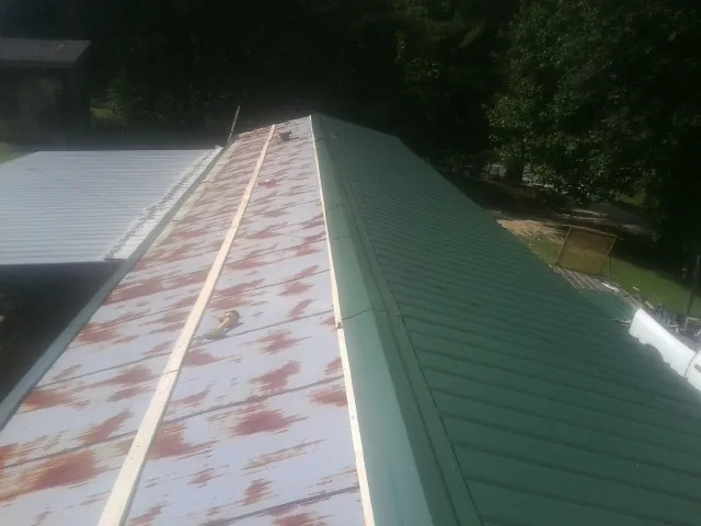 Old rusted panels beside newly installed green metal roofing — Wind Damage Roof Repair by Roofing Brothers in Hurricane Mills