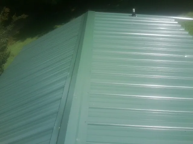 New green metal panels meeting at the ridge of a roof — Flat Roof Repair work by our crew in Hurricane Mills