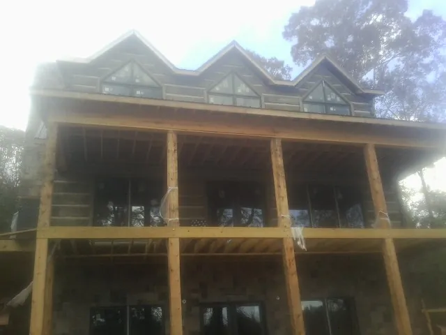 Dormers and porch framing on a large log home under construction — Roof Coating work by our crew in Hurricane Mills