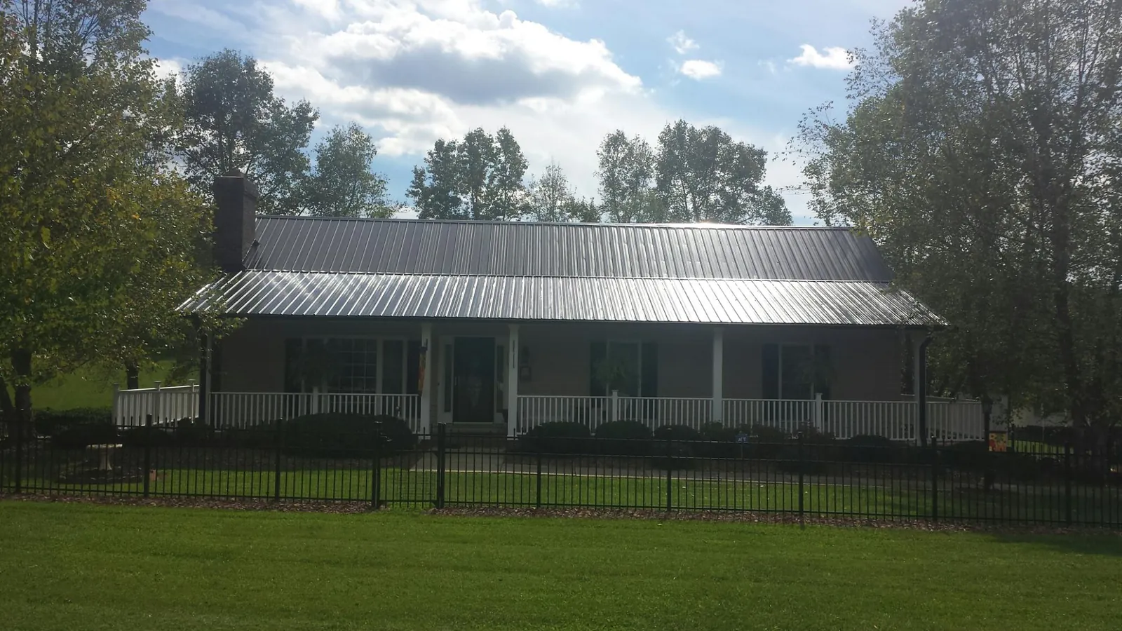 Gray metal roof on a brick ranch with a full width front porch — Gutter Guard Installation work by our crew in Hurricane Mills