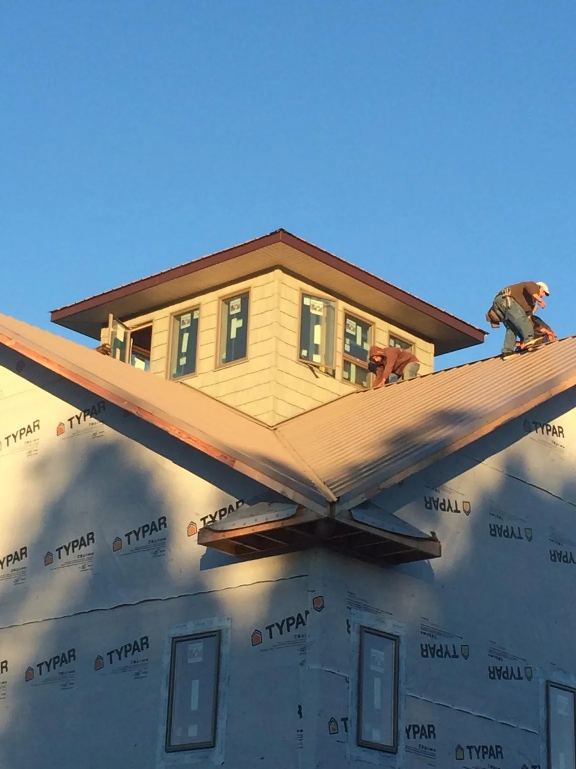 Roofers working around a rooftop cupola on a new metal roof at sunset — Roof Waterproofing in Hurricane Mills by Roofing Brothers